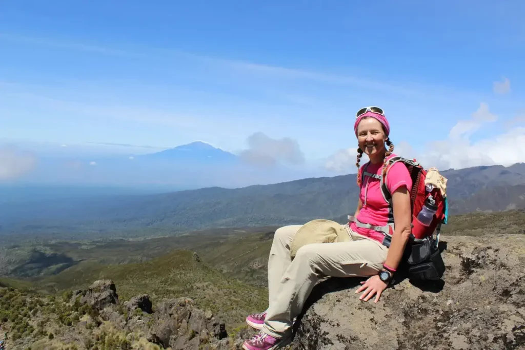 A girl trekker takes a moment to chill and admire the breathtaking surroundings on the kilimanjaro umbwe route, capturing the essence of adventure and serenity.