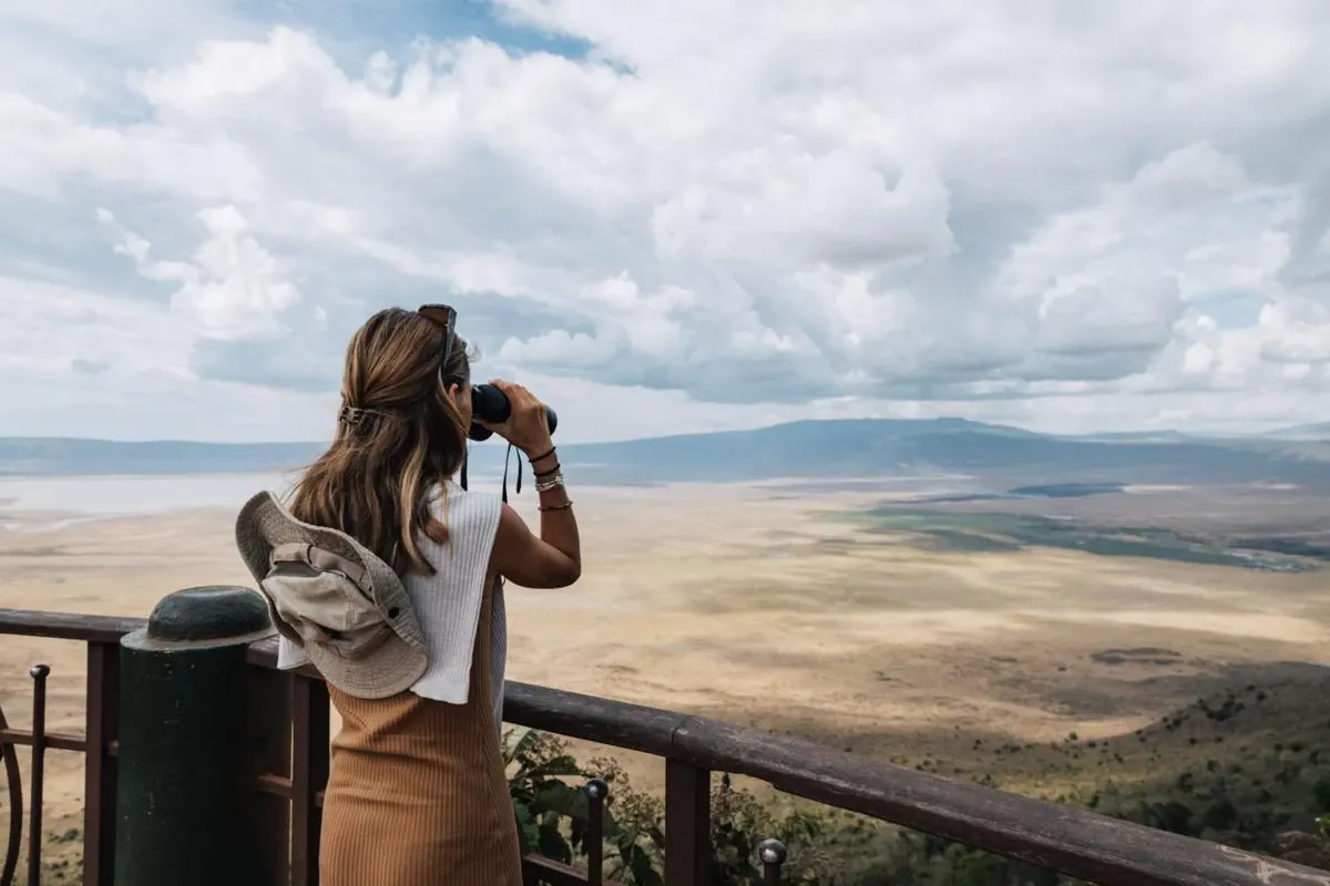 Why go ngorongoro - tourist with binoculars exploring the scenic beauty of ngorongoro crater in tanzania.